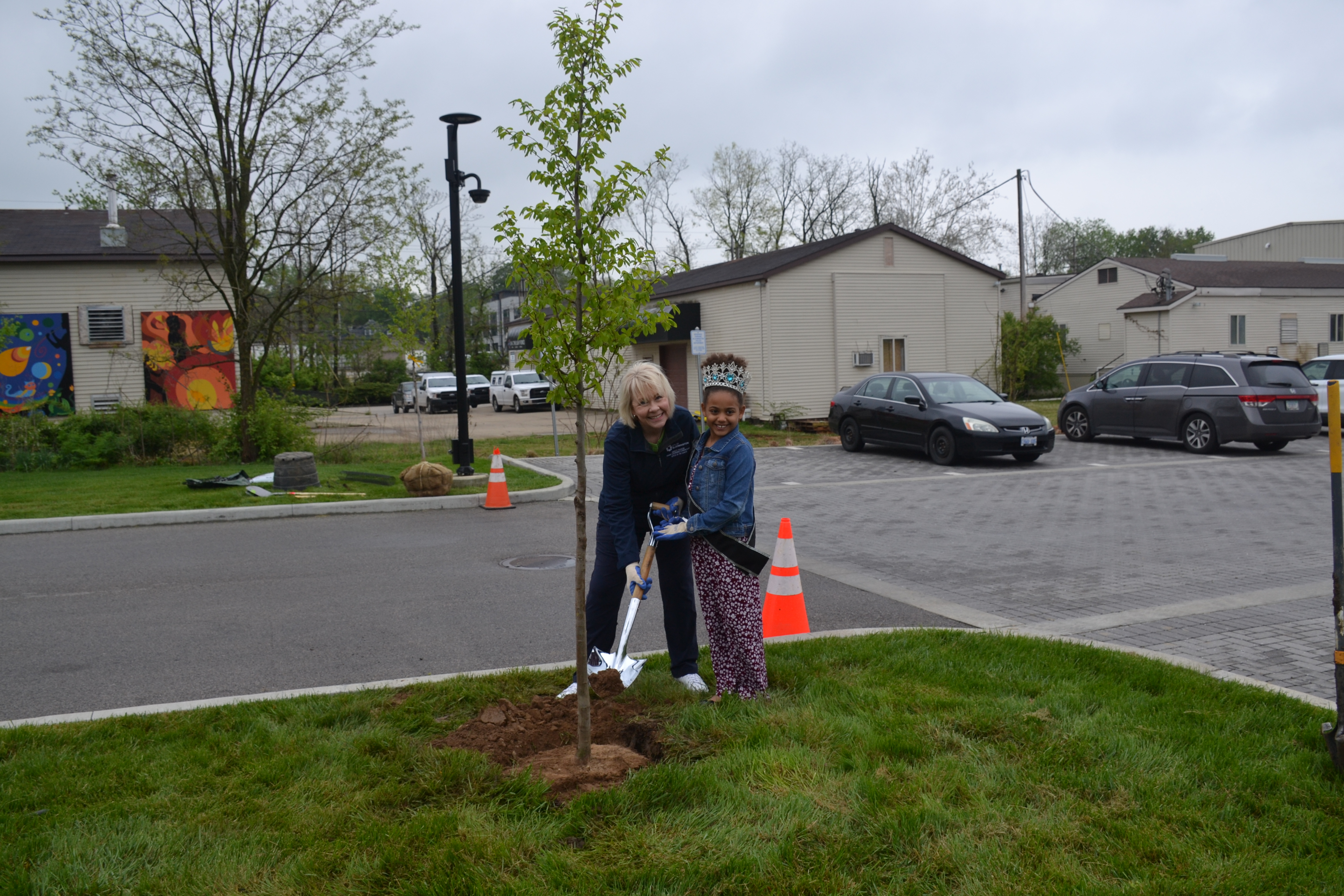 Deputy Mayor Mary Catherine Carmichael (L), with assistance from Little Miss USA Pure International Anurika Enyiaku (R), plants the 2023 Arbor Day tree, an American Hornbeam, at Switchyard Park on April 28.