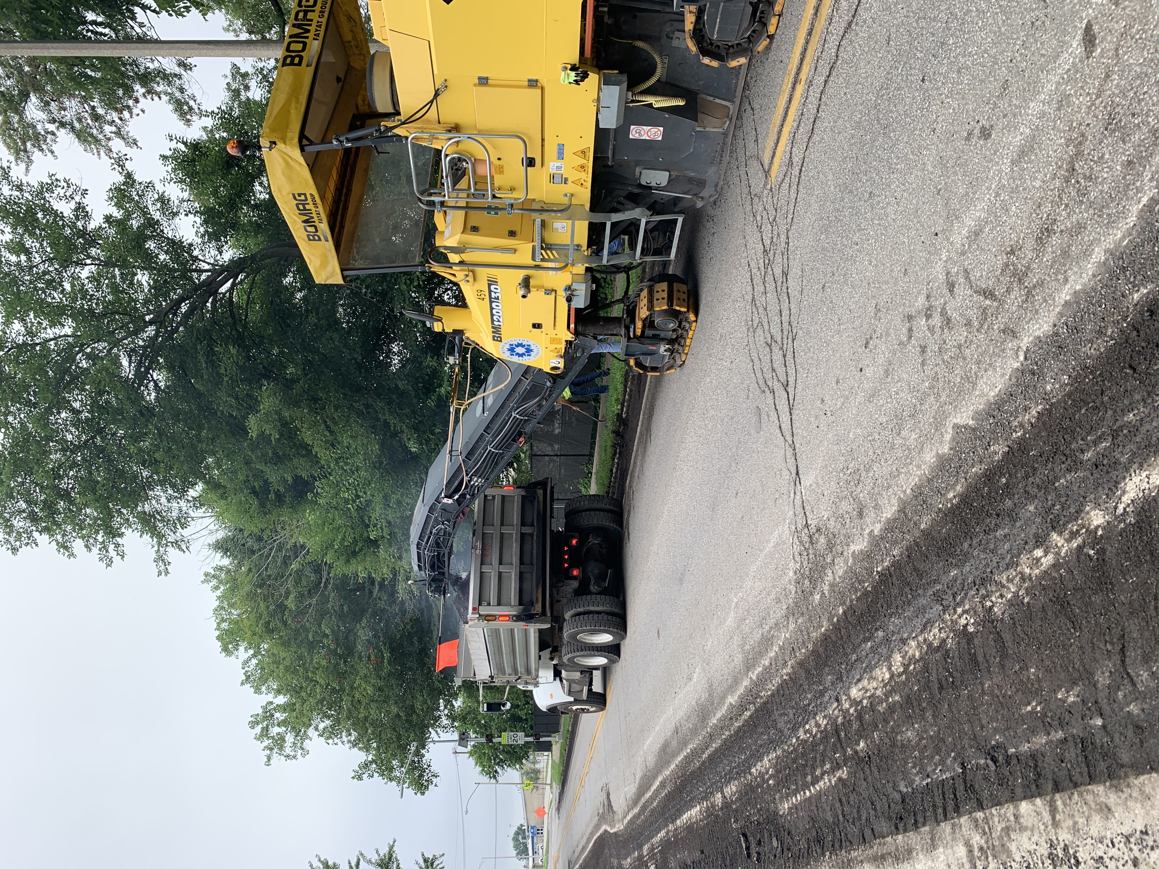 A milling machine deposits removed street material into a dump truck. 