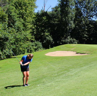 Woman golfer chips ball toward the green on the Ridge Course at Cascades Golf Course