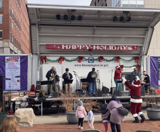 Photo of St. Nick dancing to The Dynamics at the 2022 Holiday Market in front of Bloomington's City Hall. 