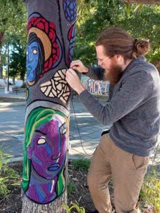 Fiber artist wrapping a tree in love
