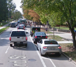 E 3rd St showing cars parked in the bike lane on the right side of road