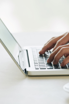 Photo of person's hands typing on laptop