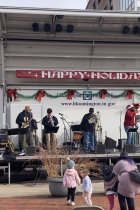 Photo of St. Nick dancing to The Dynamics at the 2022 Holiday Market in front of Bloomington's City Hall. 